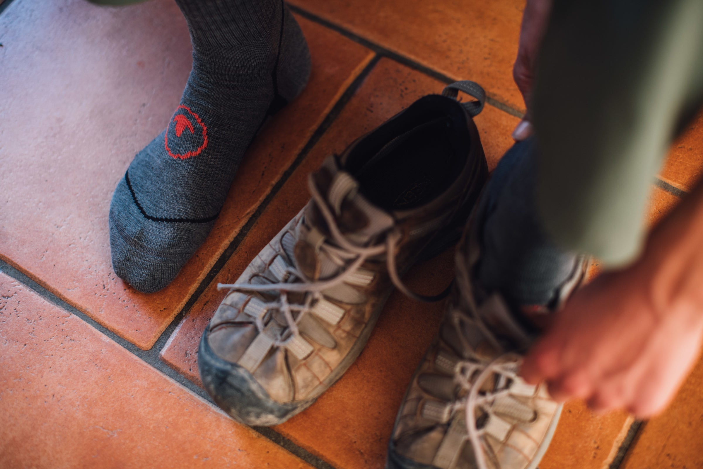 Close-up of a hiker wearing merino wool socks, preparing to put on well-worn hiking boots