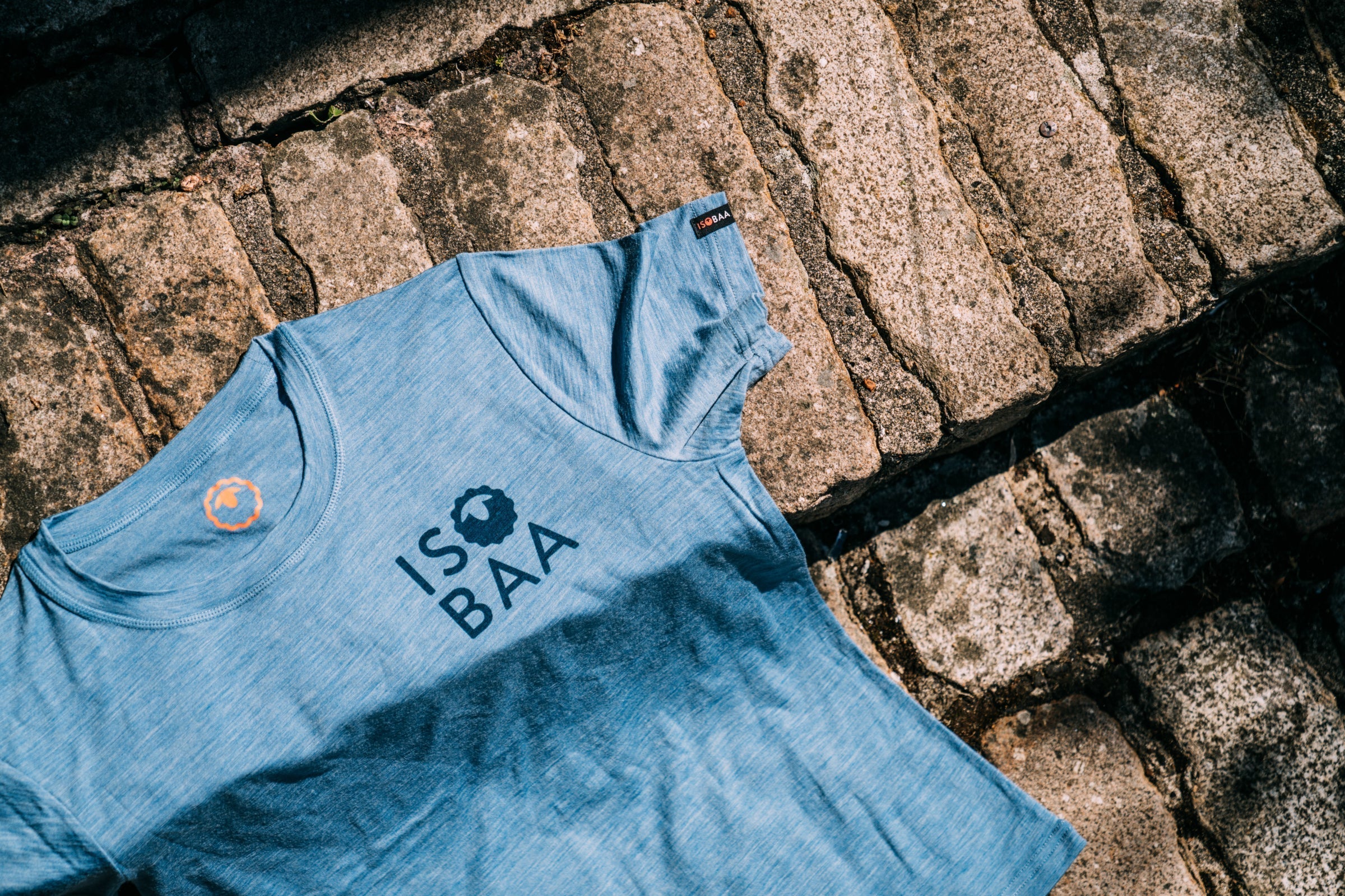 A light blue short-sleeve t-shirt laid flat on a rustic stone surface