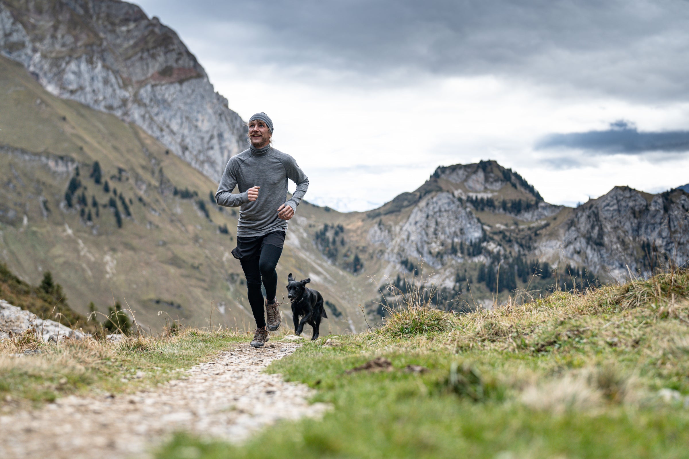 Man trail running in the mountains with a dog