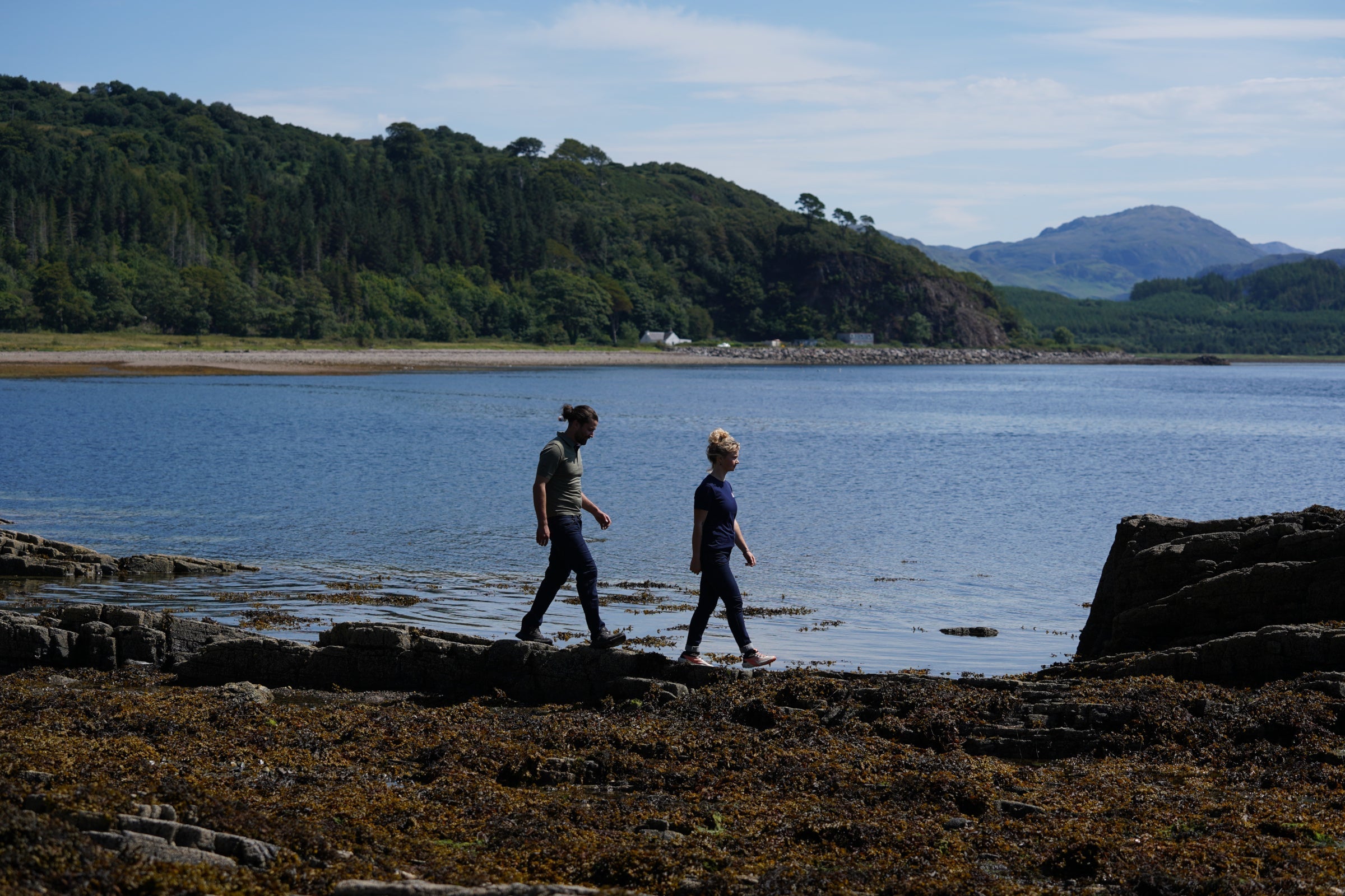 Two people walking along a rocky shoreline