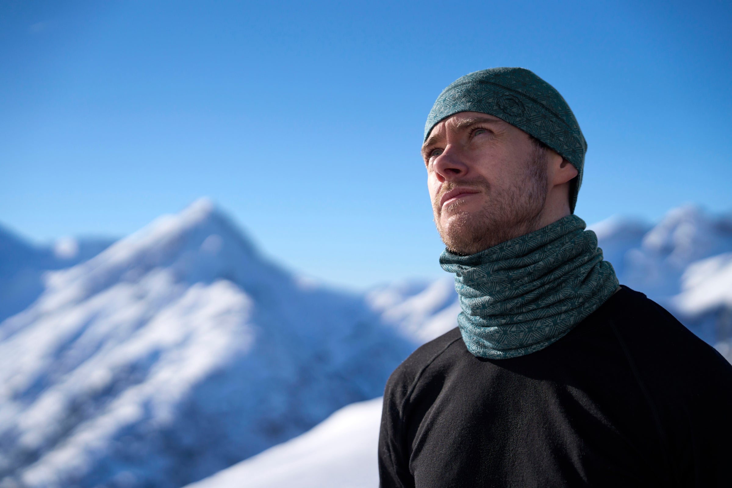 Man wearing a merino neck warmer in snowy alpine landscape