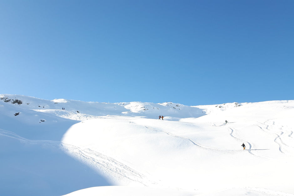 Skiers descending a snowy mountain slope