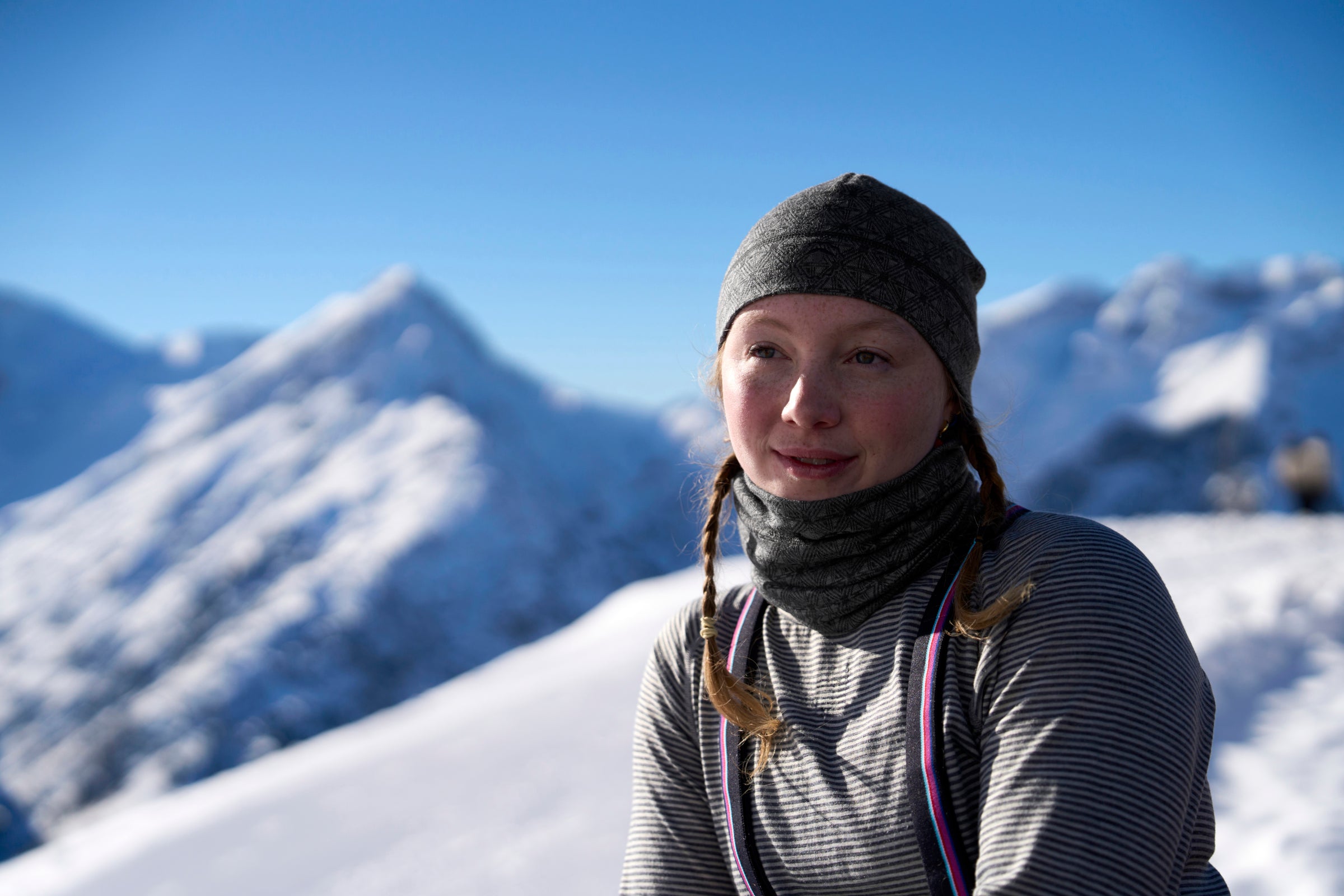 Woman wearing a merino headband and neck warmer in snowy mountains