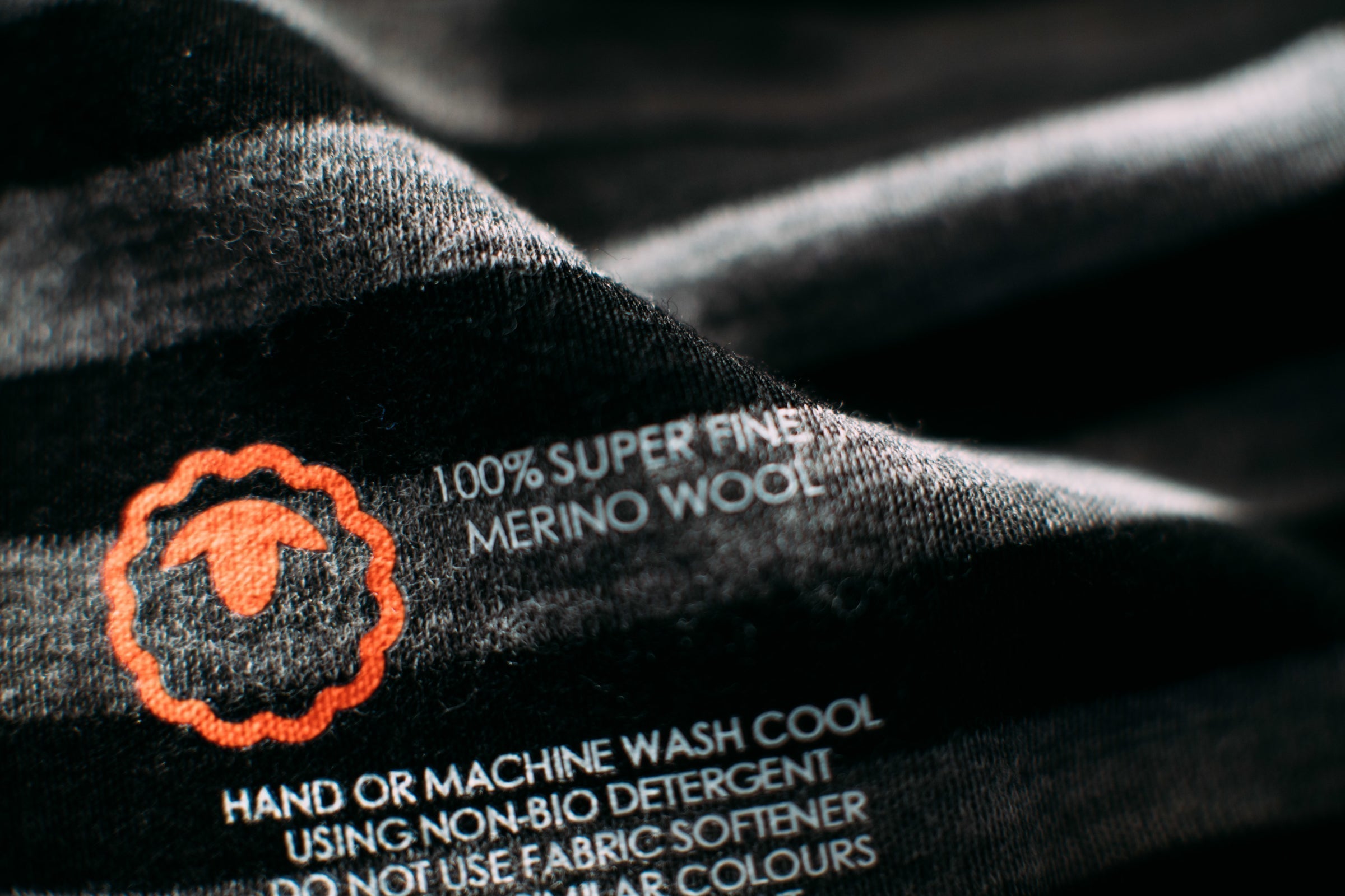 Close-up of a merino wool clothing care label showing washing instructions and fabric details
