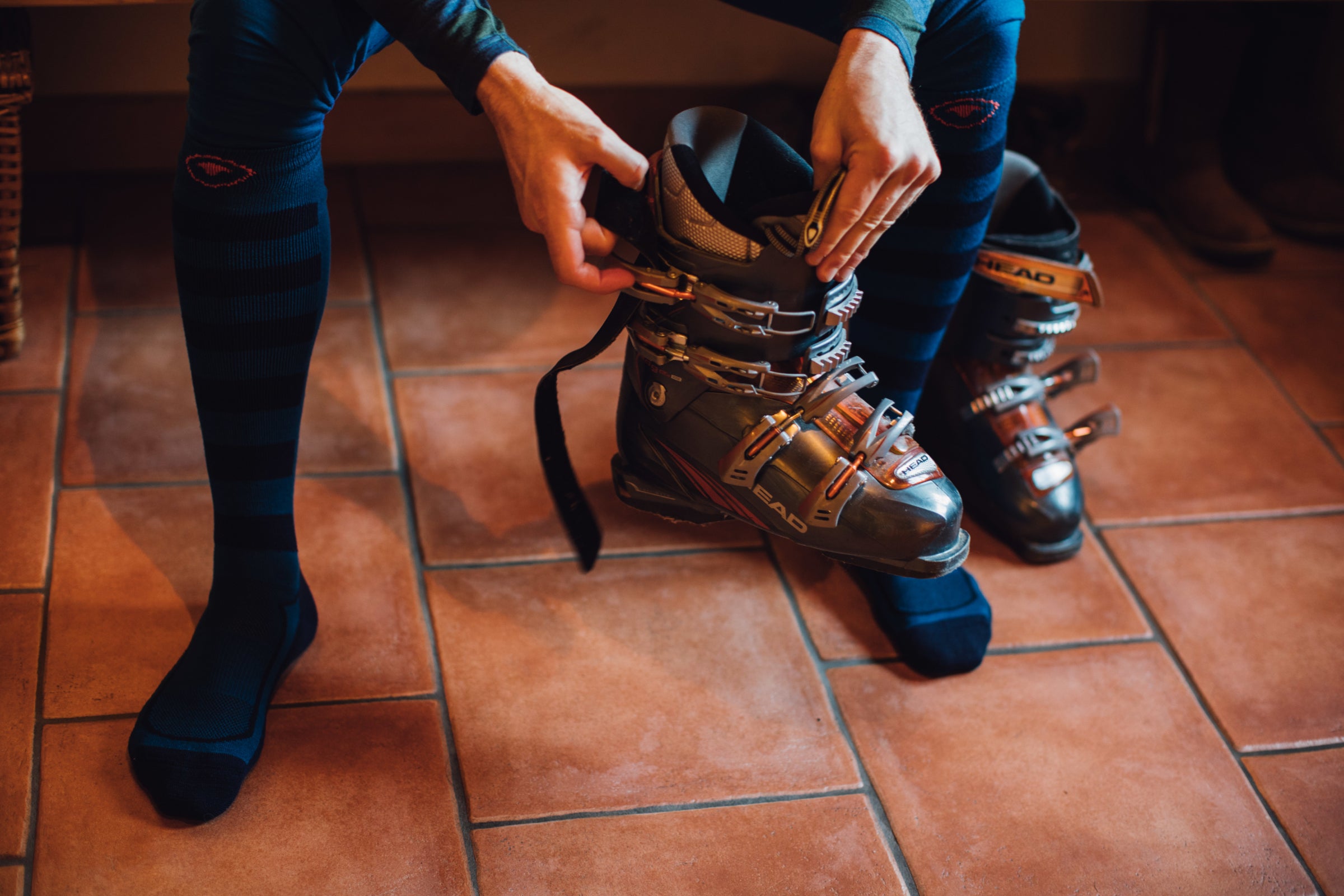 Person putting on ski boots, wearing Isobaa merino wool ski socks