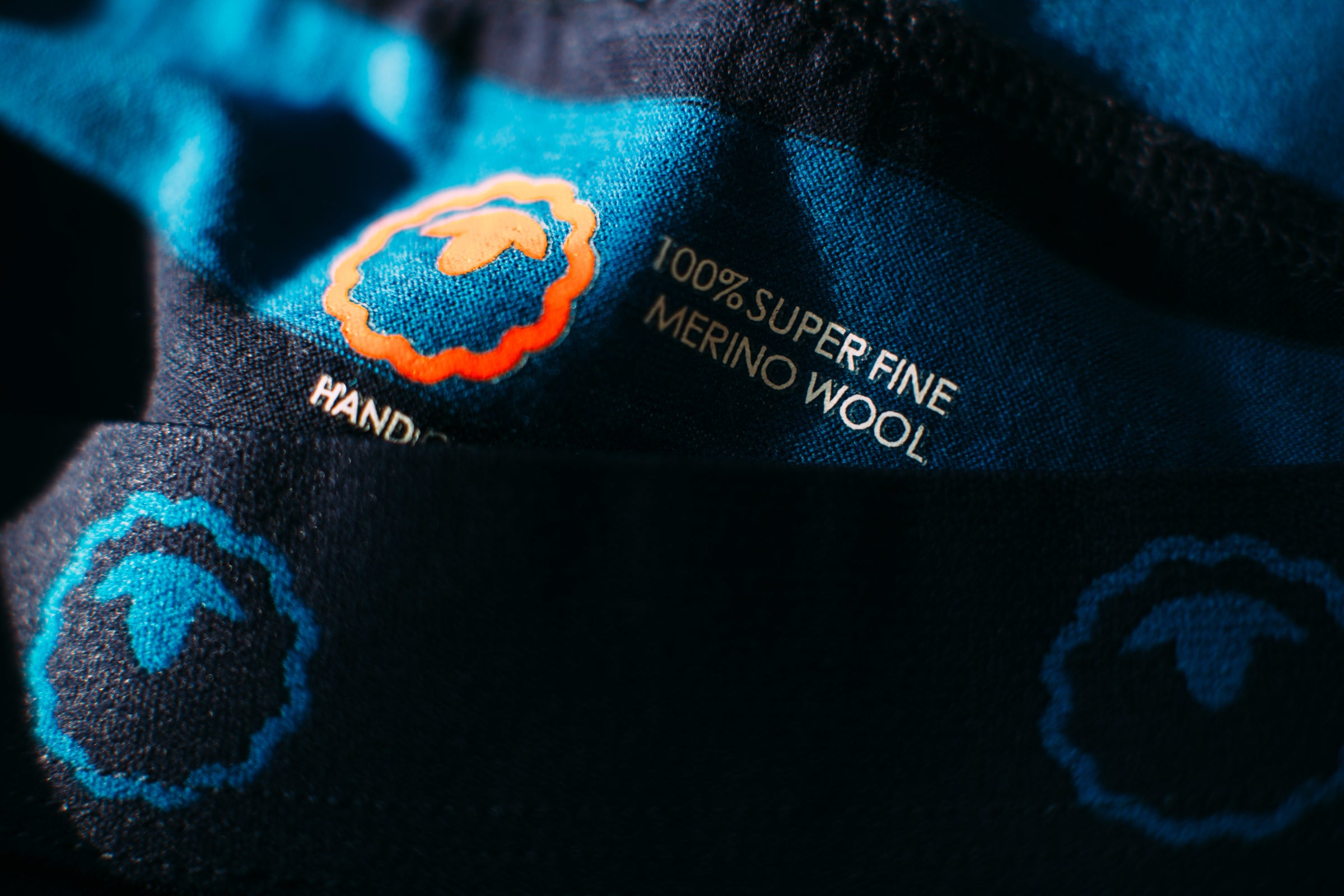 A close-up photo of a fabric tag on a Merino garment, with the text 100% Superfine Merino Wool and the logo of Isobaa