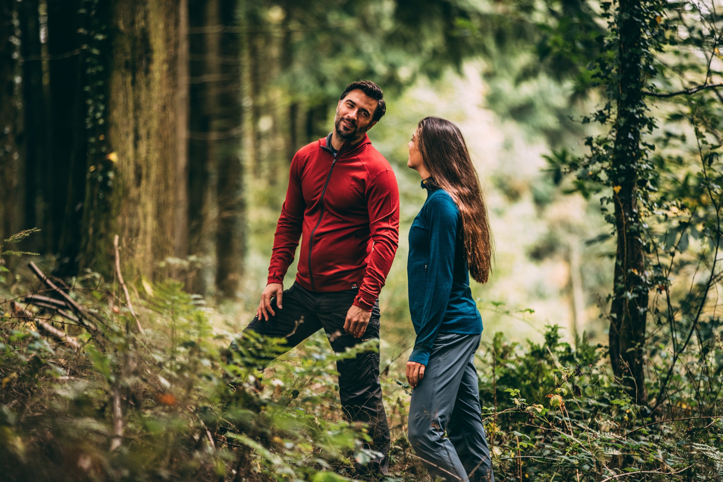Two people hiking in Isobaa red and blue tops in a forest