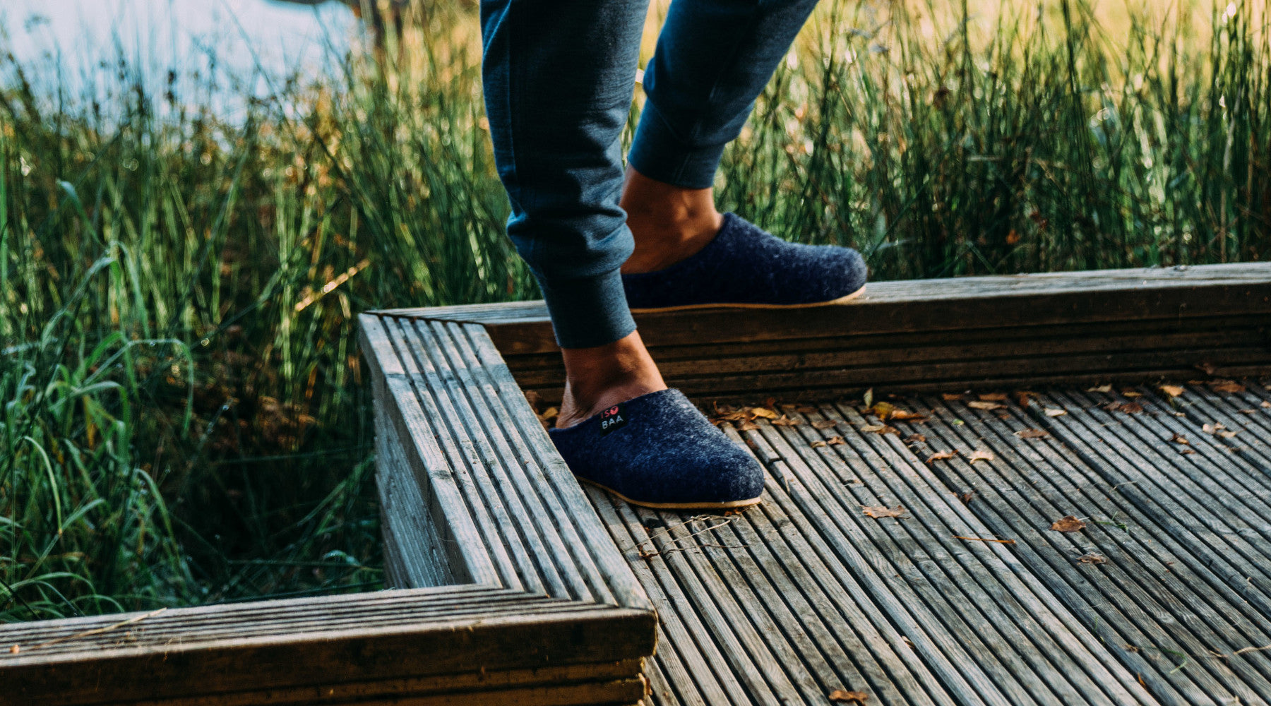 Isobaa Merino Wool Blend Slippers on wooden decking next to a pond