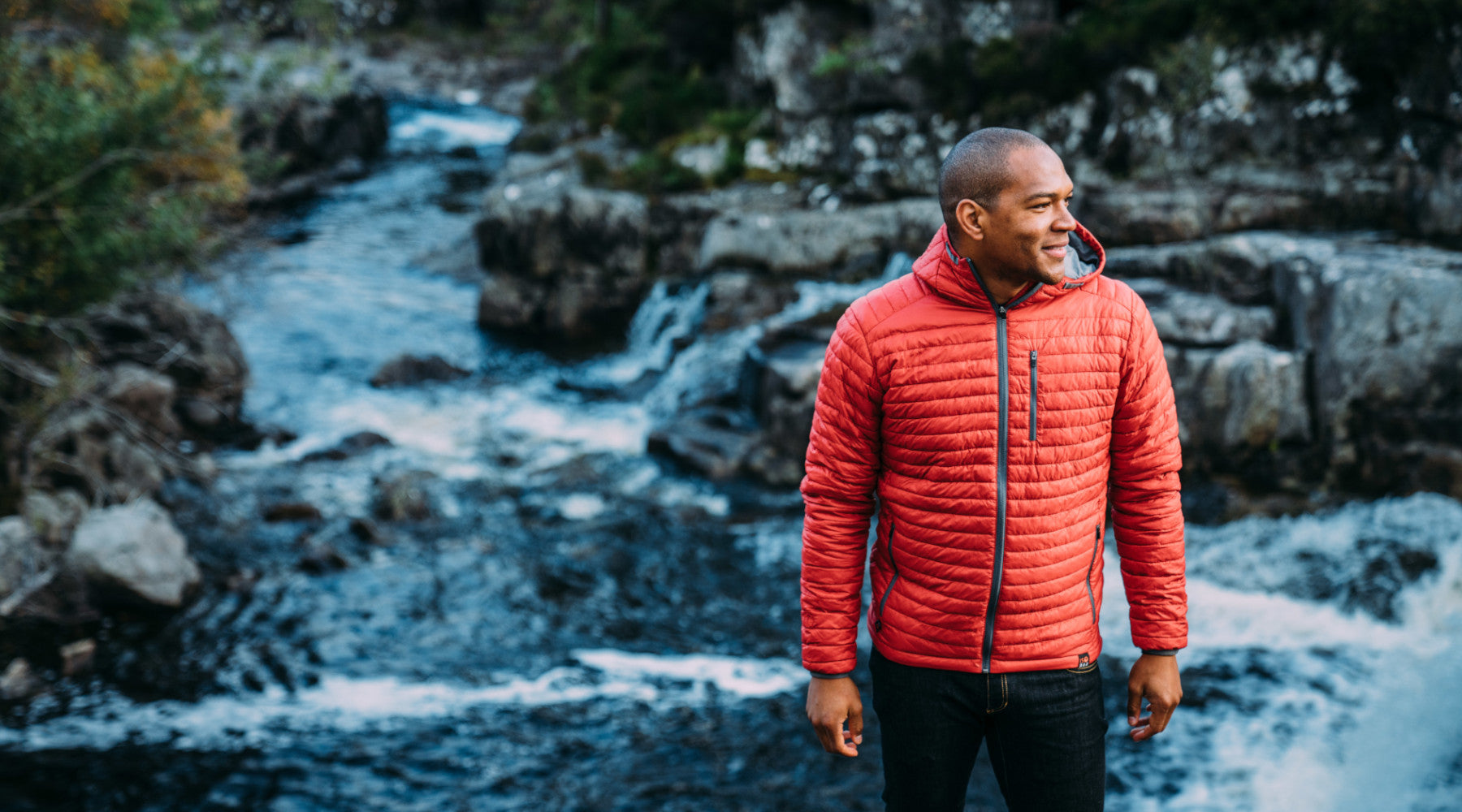 Isobaa Merino Insulated Jacket modeled next to a fast flowing stream