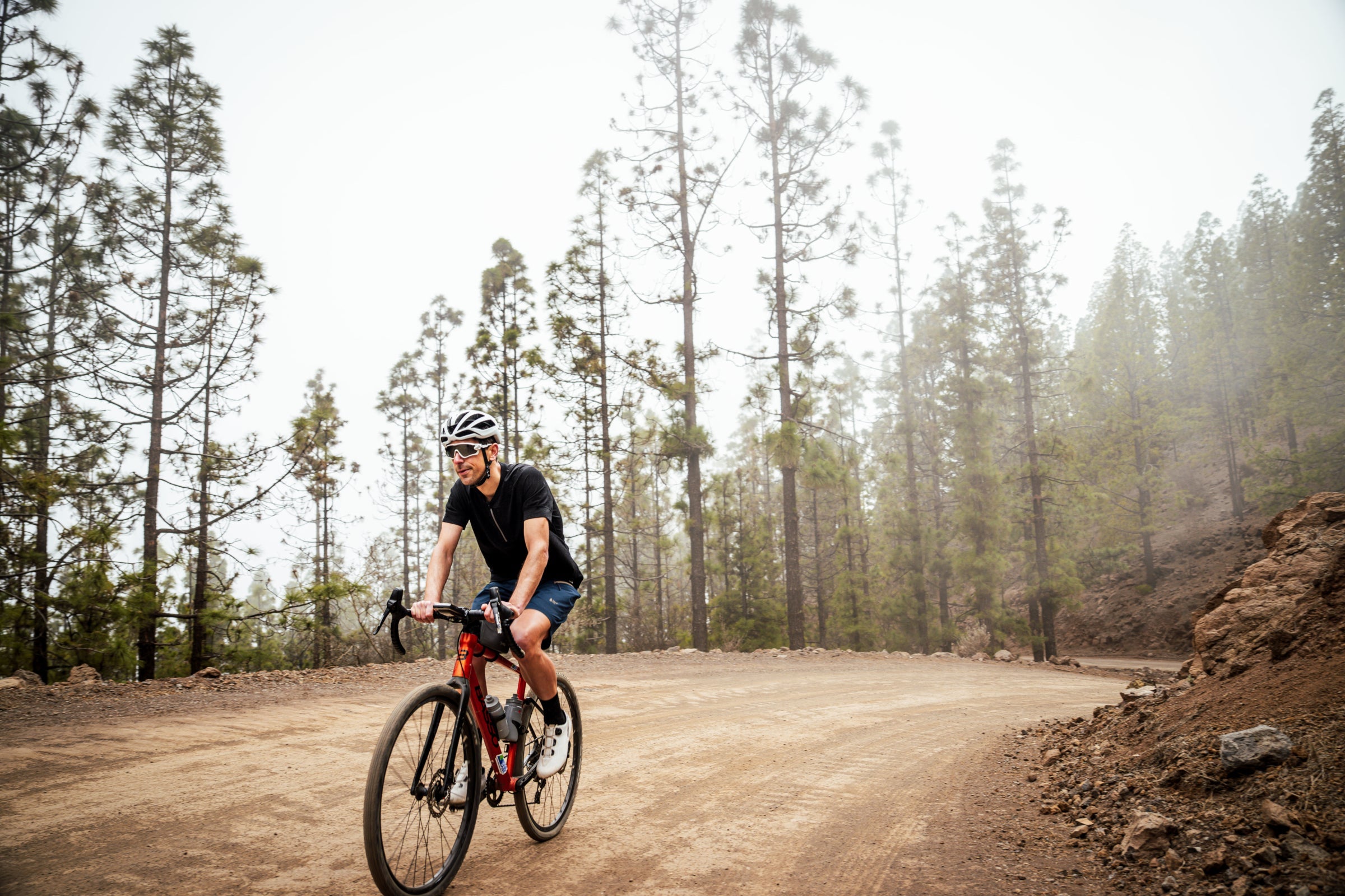 Man cycling on a dirt road through a forest