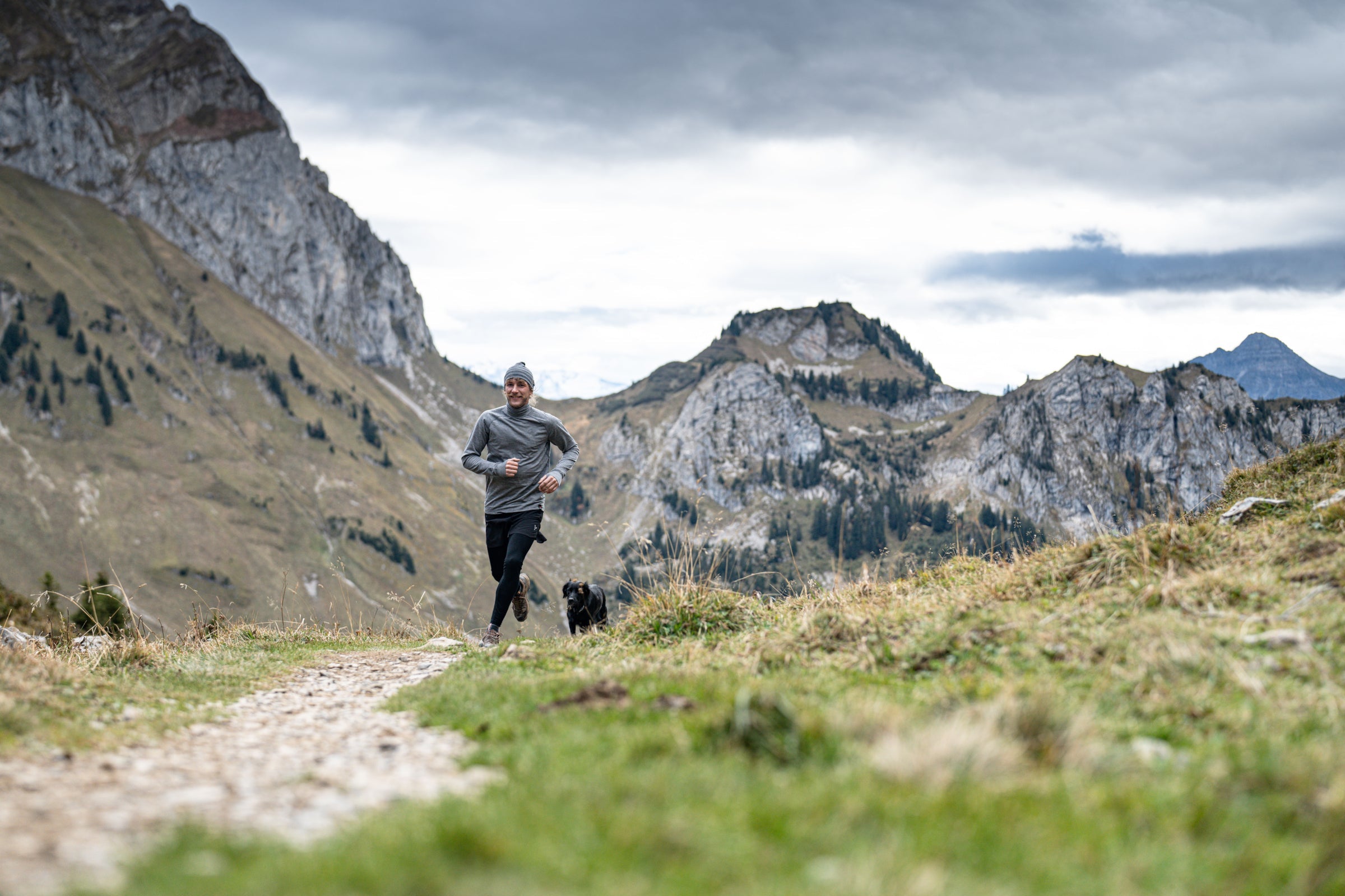 Man running on a mountain trail with a dog