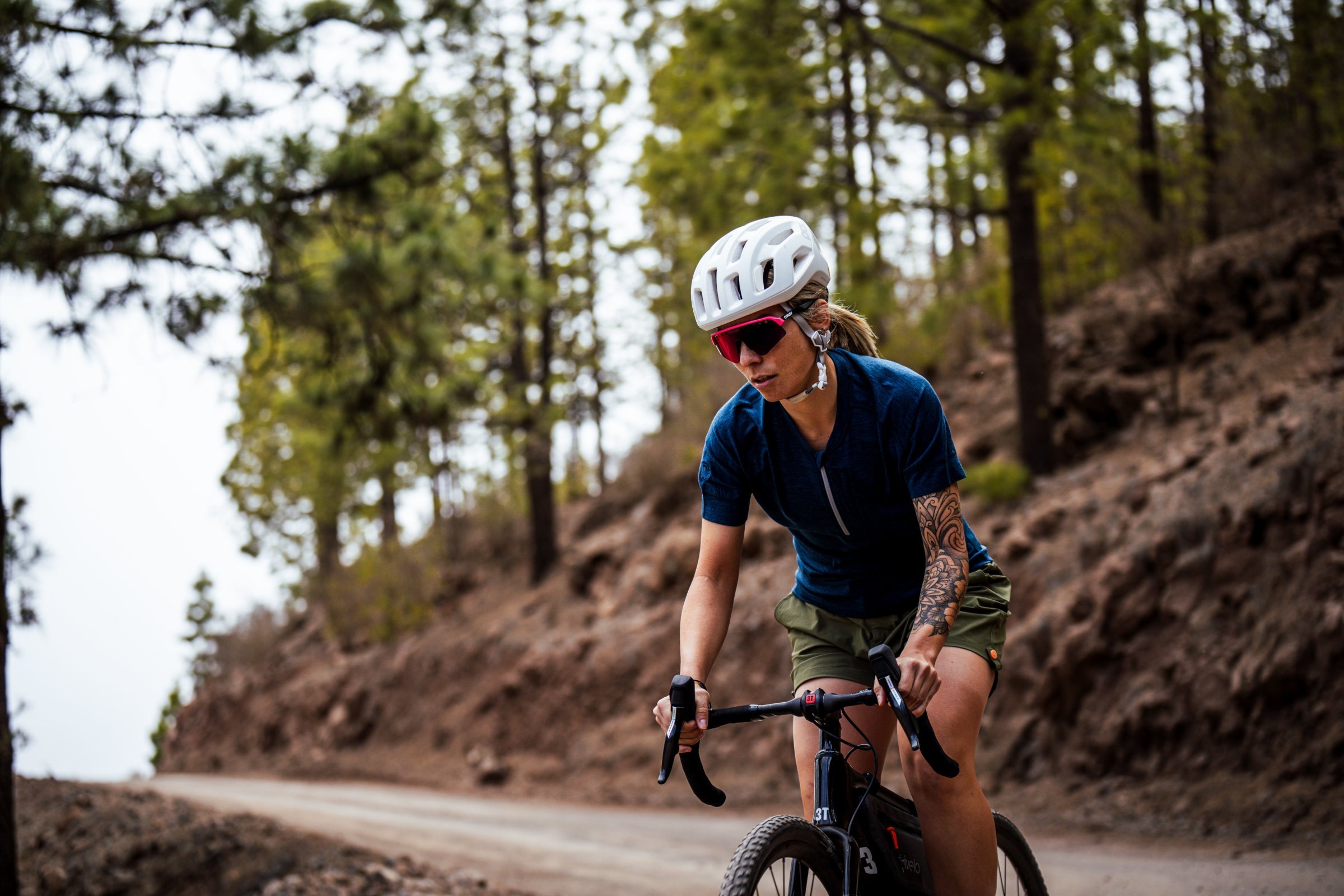 Woman cycling on a forested mountain road