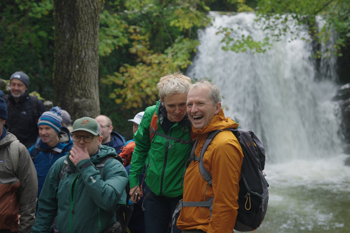 A group of people standing in front of a waterfall