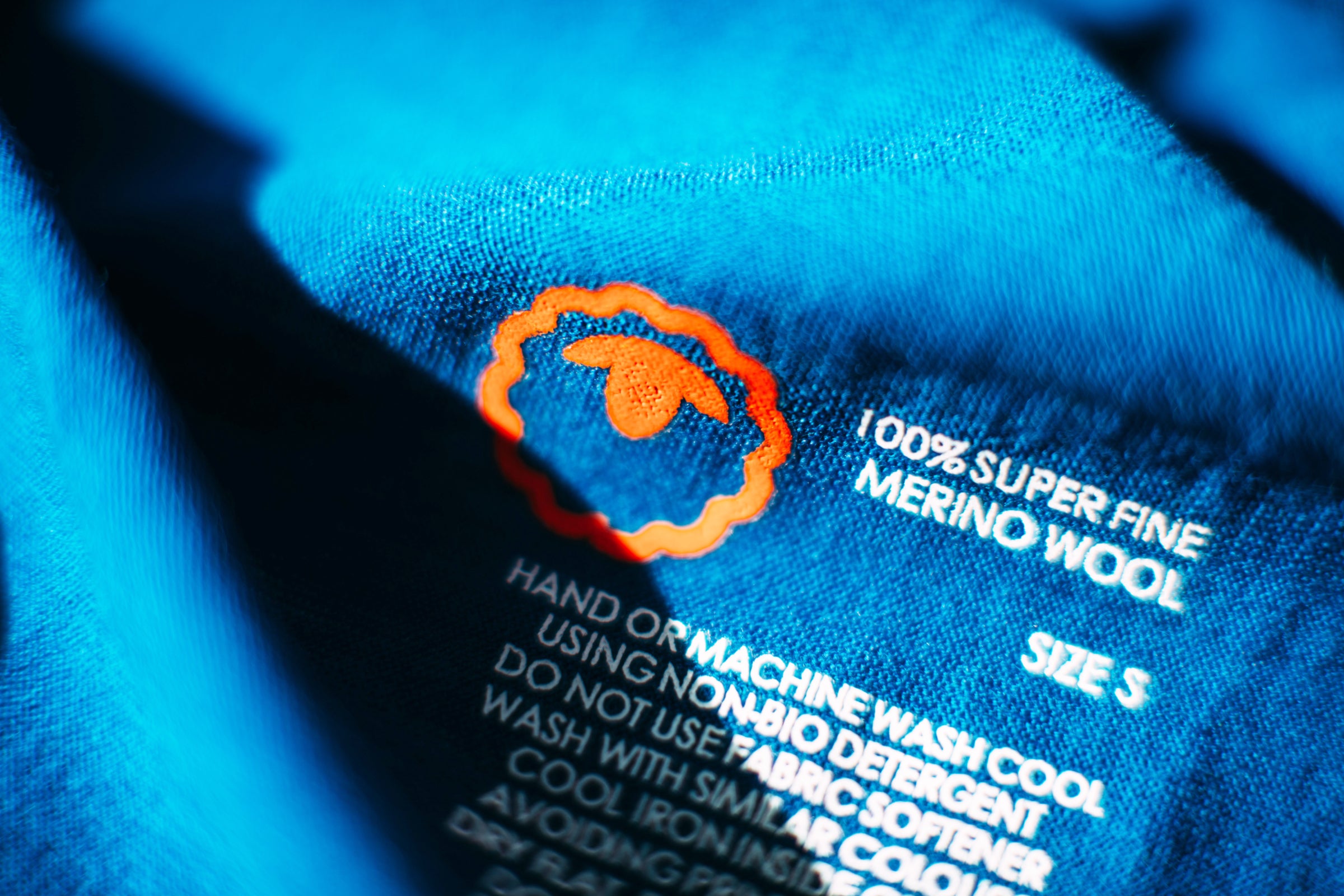 Close-up of superfine Merino wool care label on blue fabric