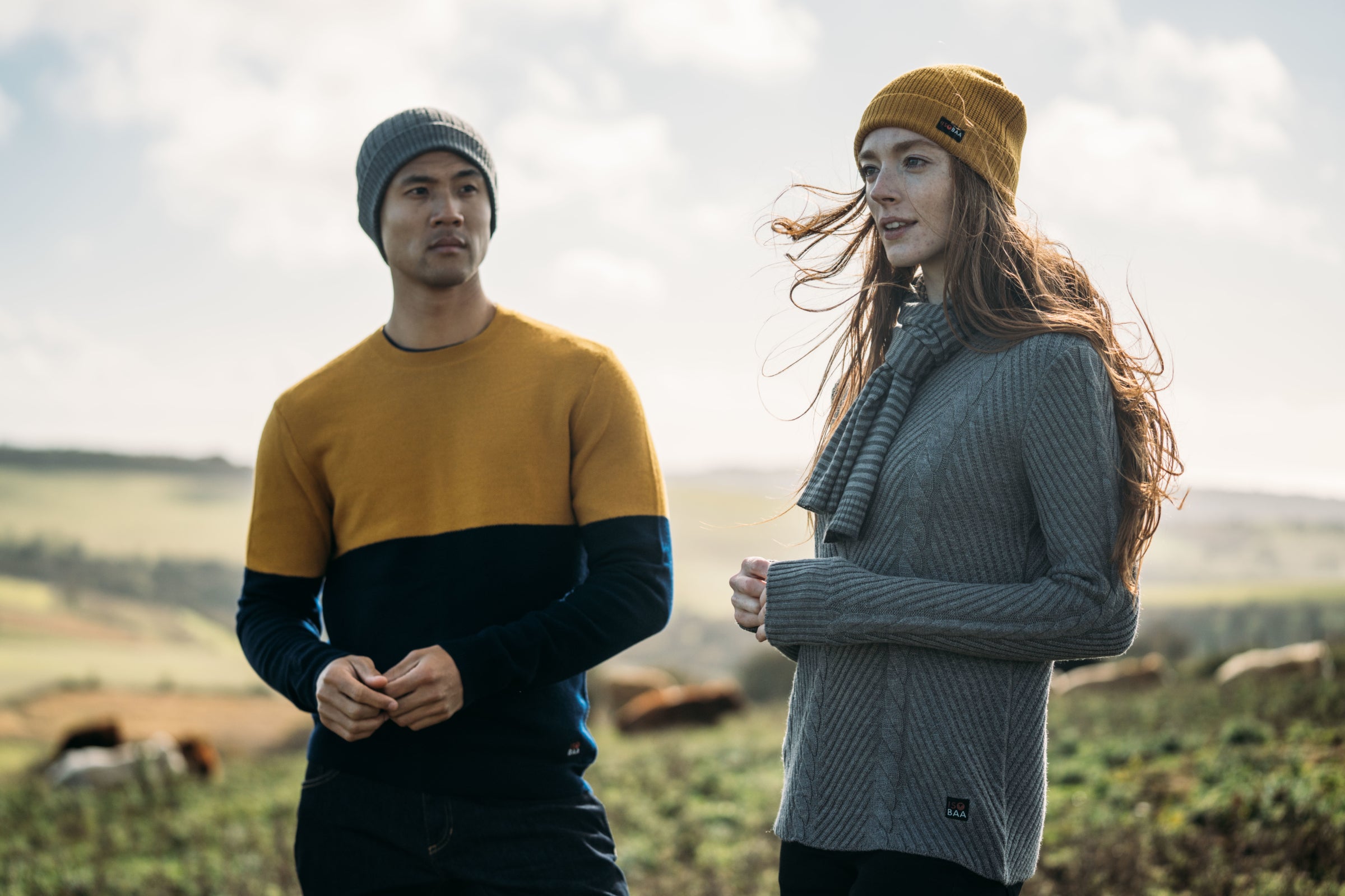 Deux personnes portant des pulls et des bonnets colorés dans un champ